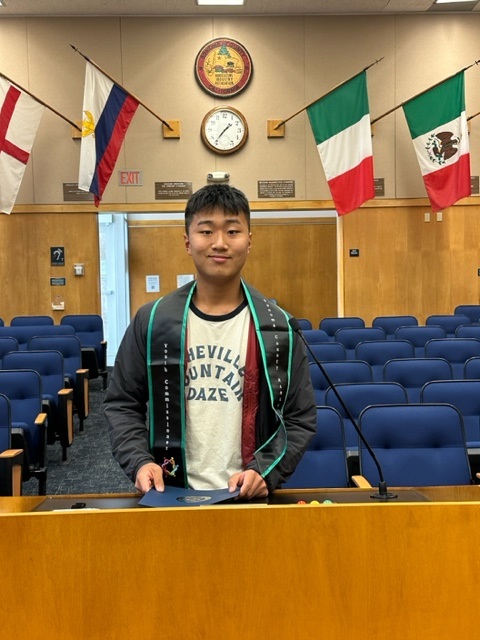 Matthew standing in front of seats and flags displaying on top 