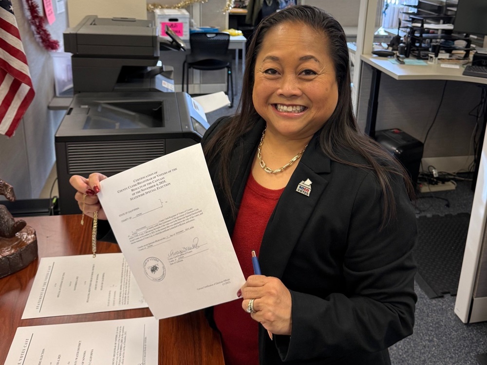 Evelyn Mendez, the Sonoma County Registrar of Voters, smiles in the Registrar of Voters office while holding up election certification paperwork that she just signed.