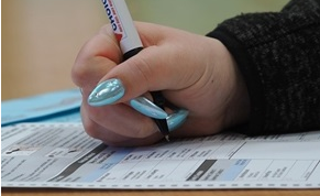 A closeup of someone's hand filling out a ballot