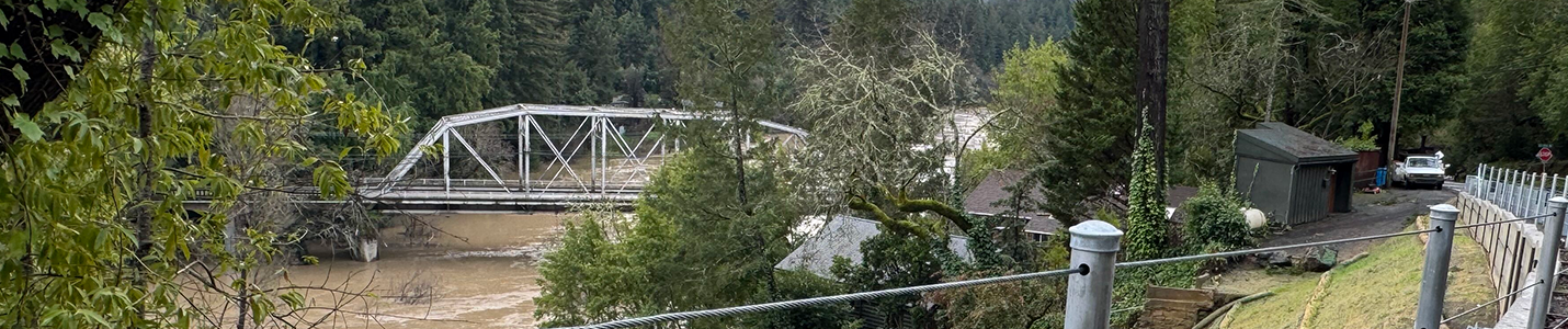 Steel truss bridge over rising river after rainstorm
