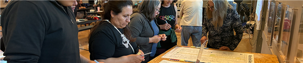 People surrounding a table with maps they can leave comments on.