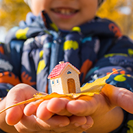 Child holding toy house in cupped hands