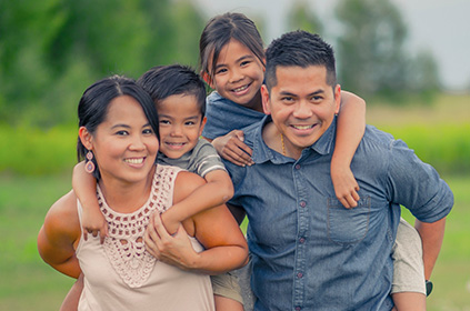 Young asian family with mom and dad carrying young children piggyback